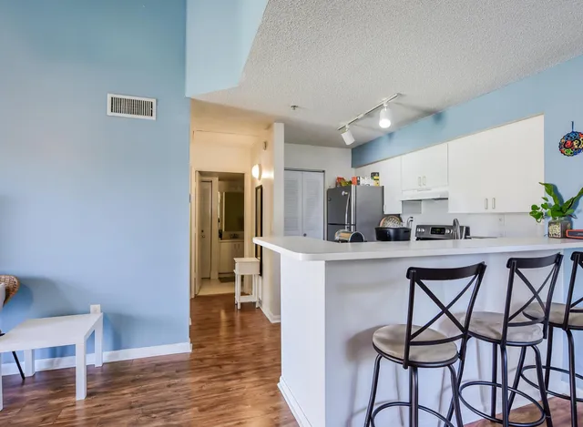 a kitchen with stainless steel appliances a table and chairs in it