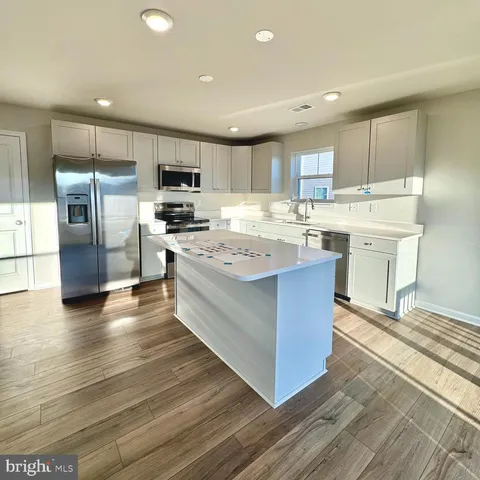 a large kitchen with stainless steel appliances kitchen island granite countertop a stove and a refrigerator