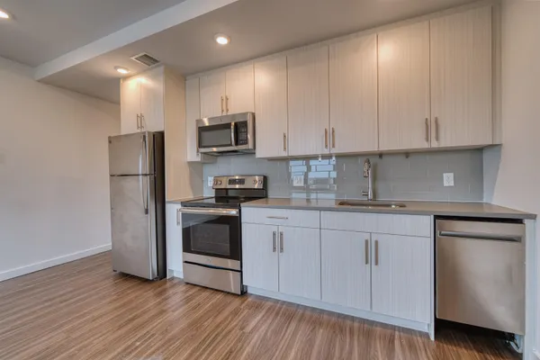 a kitchen with stainless steel appliances granite countertop white cabinets a sink a stove a refrigerator and white cabinets