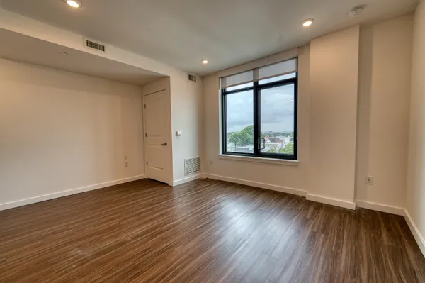 a view of an empty room with wooden floor and a window