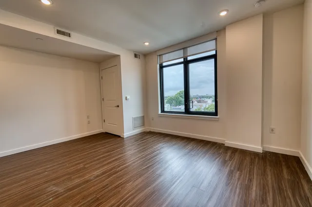 a view of an empty room with wooden floor and a window