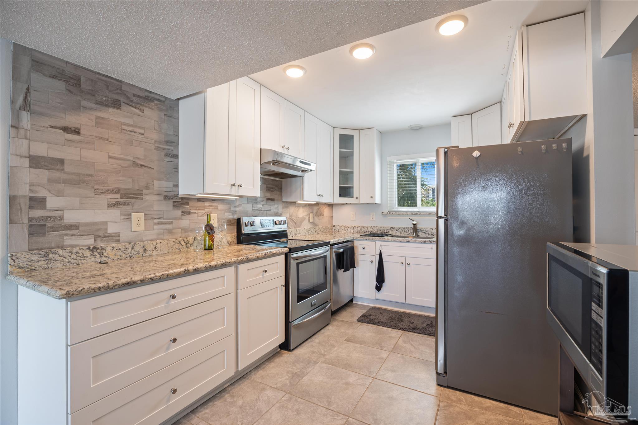 14100 River Road, Unit 228B Pensacola, FL 32507 - Photo 9 of 41 a kitchen with stainless steel appliances granite countertop a refrigerator sink and cabinets