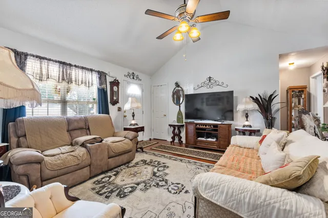 a living room with furniture a flat screen tv and a chandelier