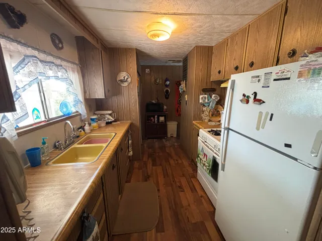 a kitchen with granite countertop a refrigerator a sink a stove and wooden floor