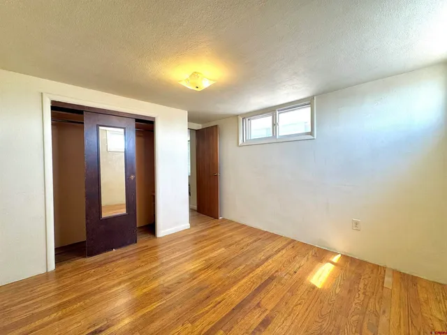 a view of an empty room with wooden floor and closet