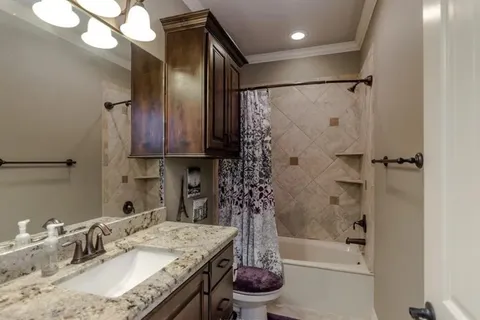 a bathroom with a granite countertop sink a toilet and shower