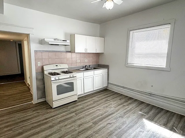 a kitchen with a stove white cabinets and wooden floor