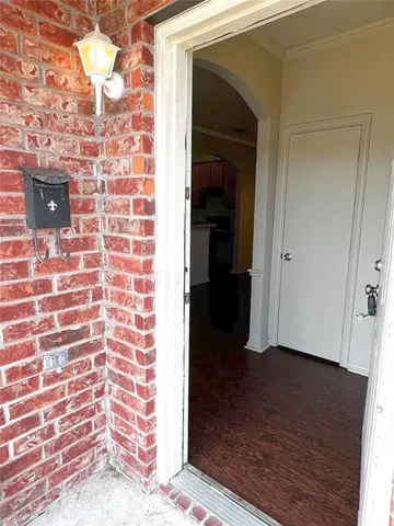a view of a hallway with wooden floor and a bathroom