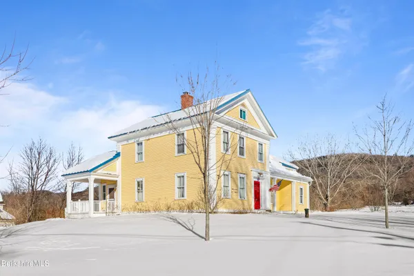 a front view of a building with large trees