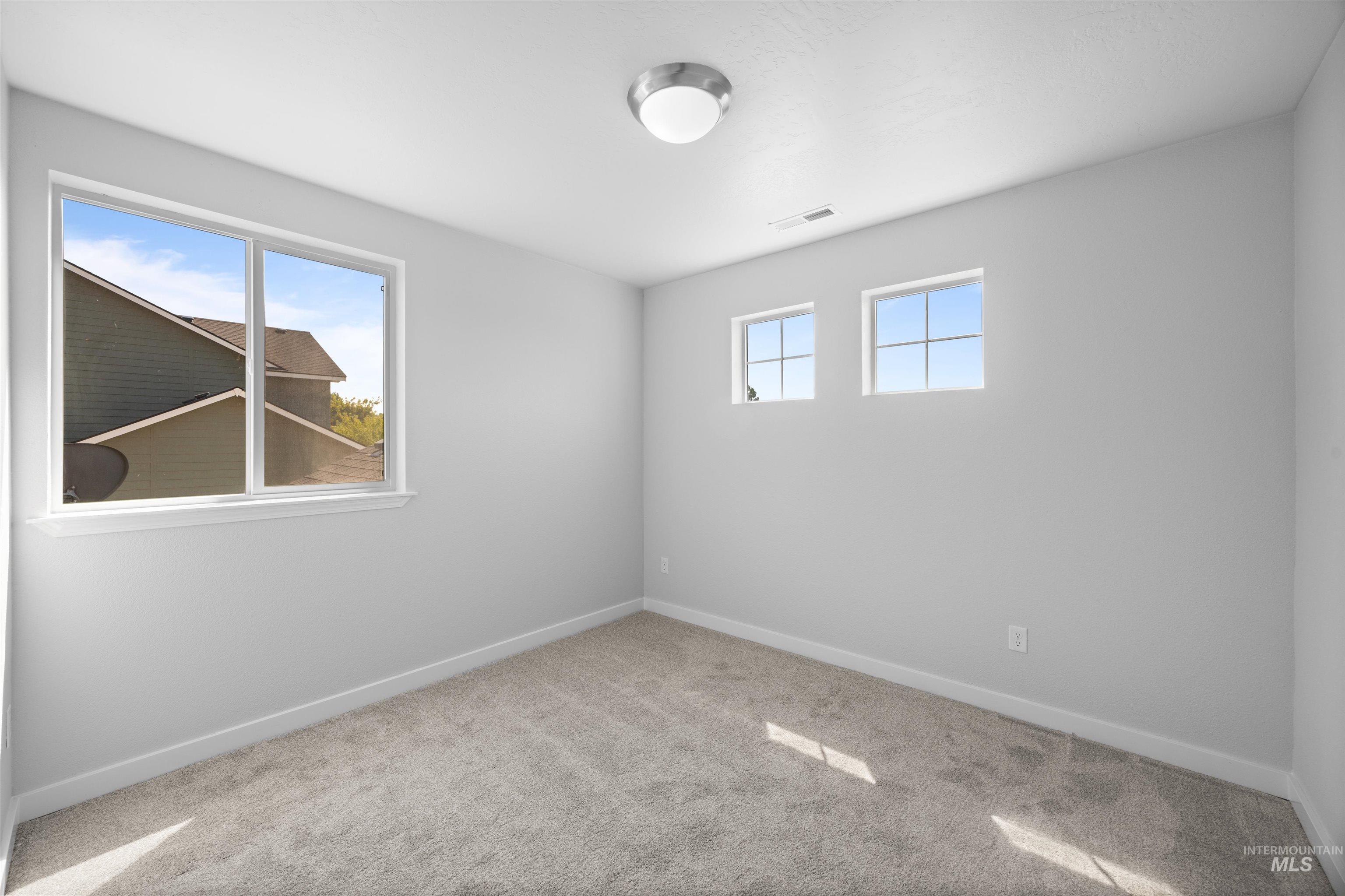 300 South Rocker Avenue Kuna, ID 83634 - Photo 23 of 49 Carpeted room featuring a large picture window, two smaller transom windows, a flush-mount ceiling light, white baseboards, and neutral wall tones
