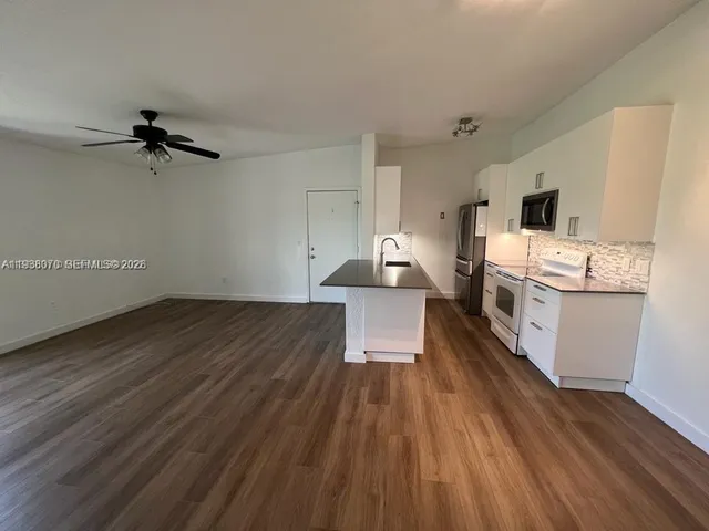 a view of a kitchen with a sink a ceiling fan and wooden floor