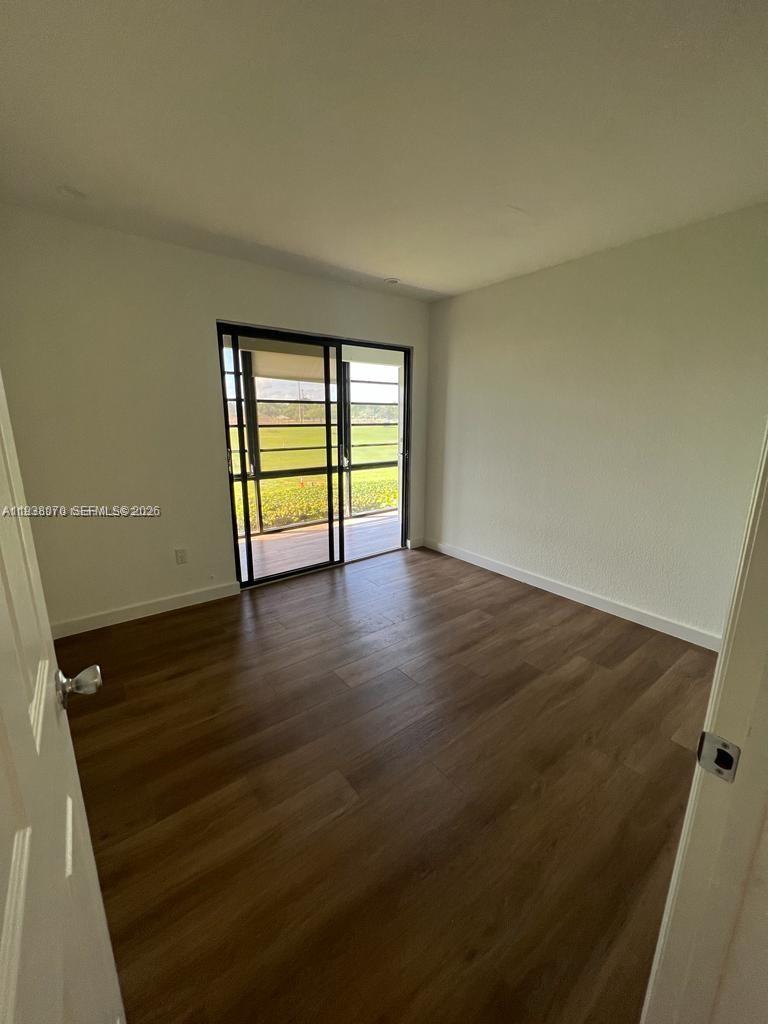 9727 Hammocks Boulevard, Unit 202D Miami, FL 33196 - Photo 7 of 16 an empty room with wooden floor and windows