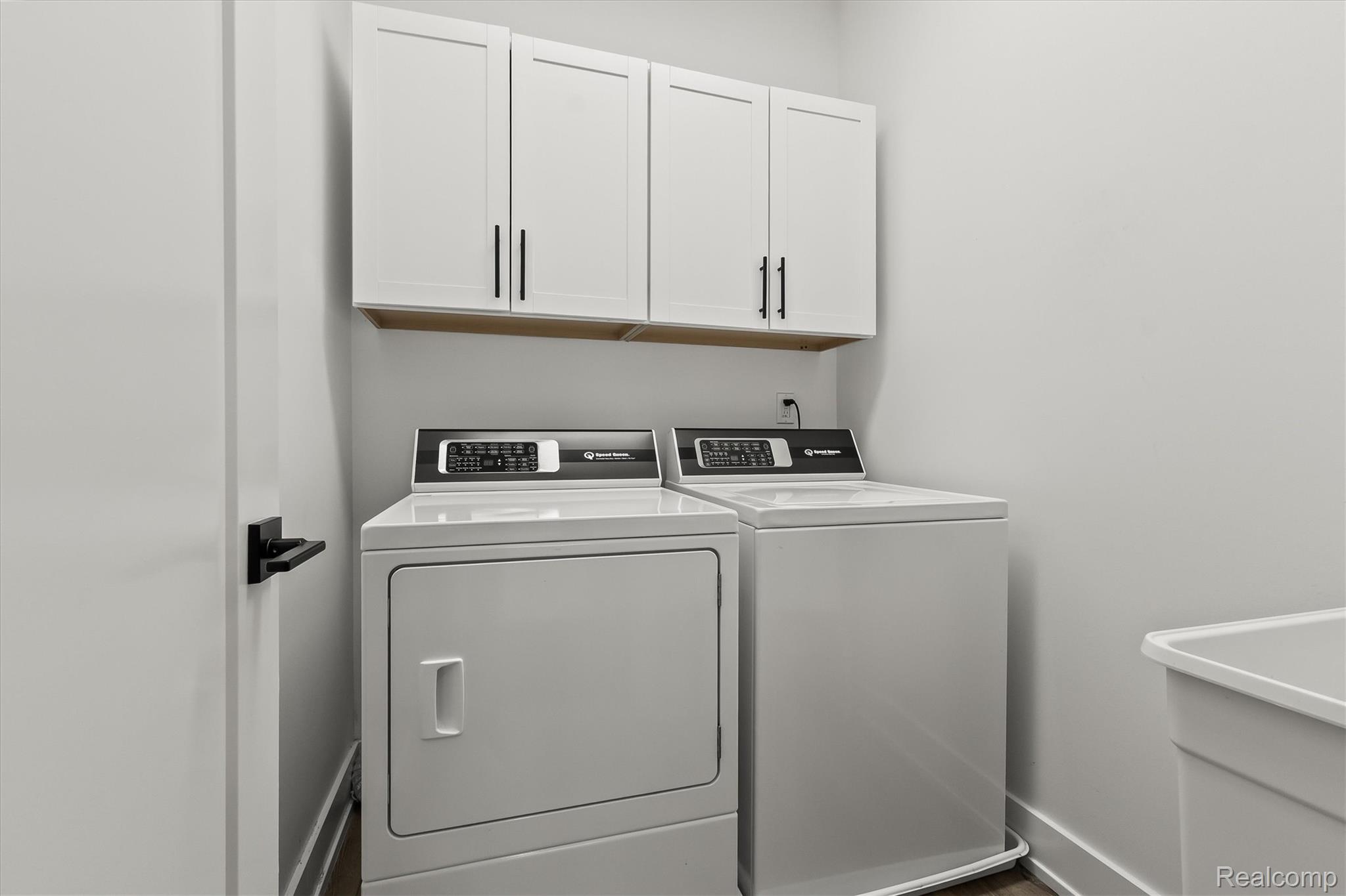 2554 Middleton Street Rochester, MI 48309 - Photo 19 of 38 Dedicated laundry area featuring white shaker-style cabinetry with matte black hardware, a utility sink, and wood-finish flooring