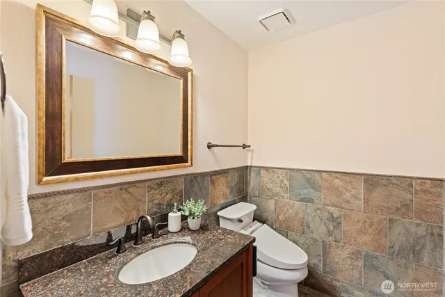 a bathroom with a granite countertop sink mirror vanity and toilet