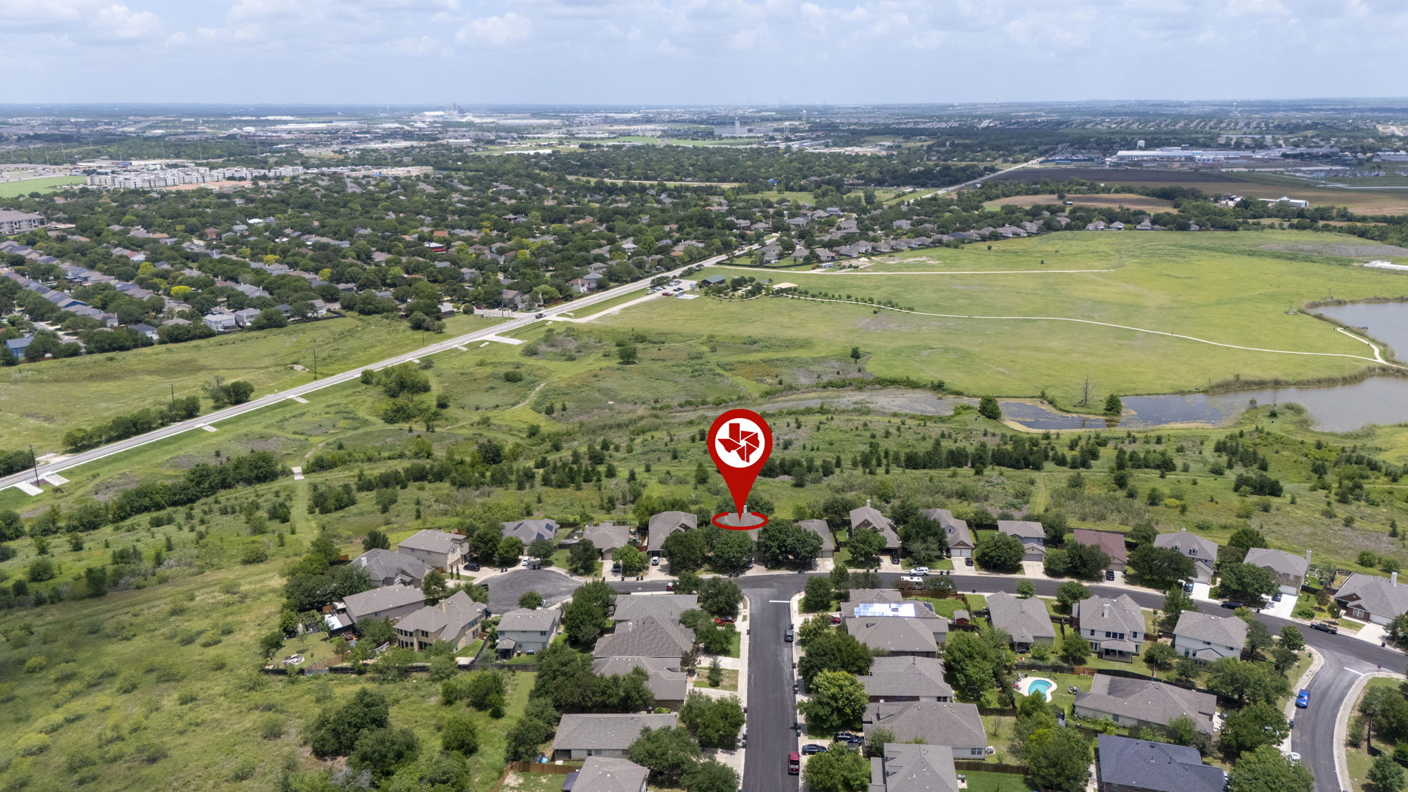 454 Fall Circle Kyle, TX 78640 - Photo 2 of 39 An aerial panorama reveals a residential neighborhood nestled beside green spaces and water features.
