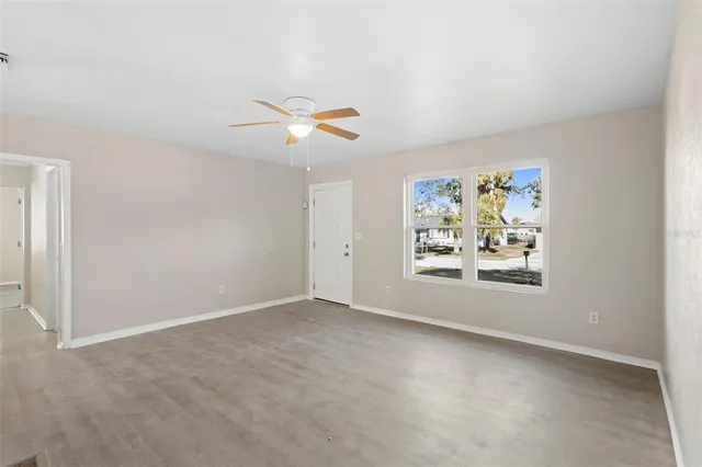 an empty room with window and ceiling fan