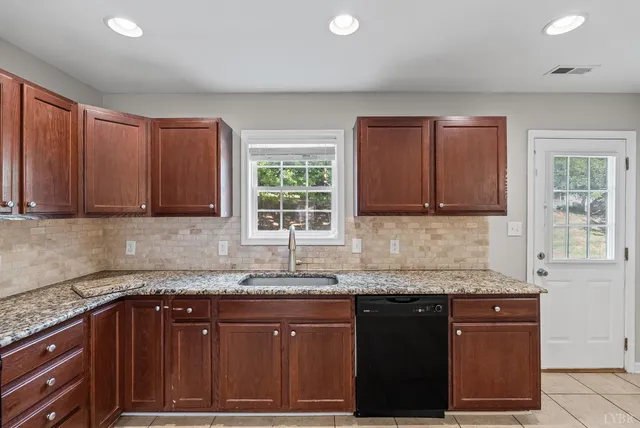 a kitchen with granite countertop wooden cabinets a sink and a window