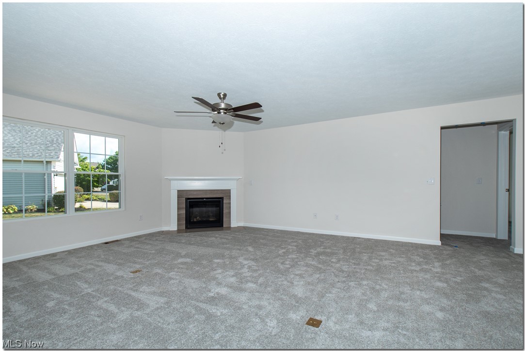 7701 Webster Road Middleburg Heights, OH 44130 - Photo 14 of 29 Unfurnished living room featuring carpet floors, ceiling fan, and a tile fireplace
