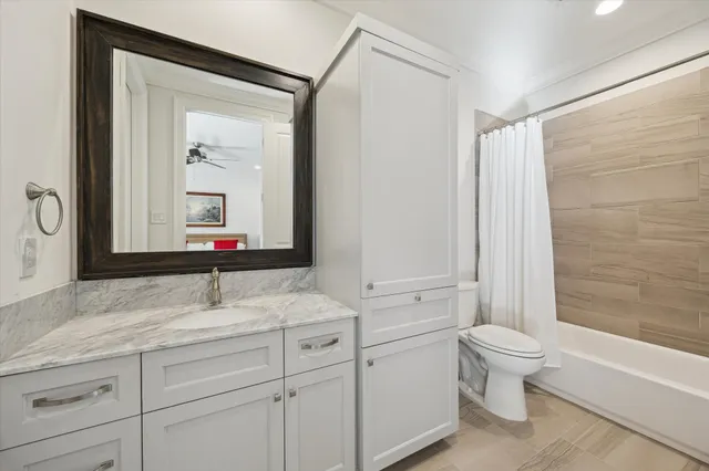 a bathroom with a granite countertop sink toilet mirror and bathtub