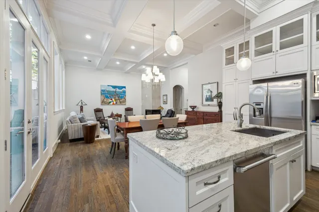 a open kitchen with a stove a sink dishwasher and a dining table with wooden floor