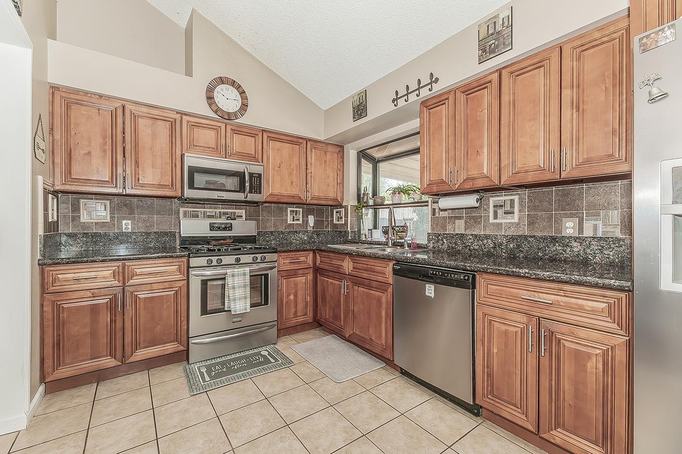 1908 East Niles Avenue Fresno, CA 93720 - Photo 9 of 30 a kitchen with stainless steel appliances granite countertop a stove a sink and a microwave