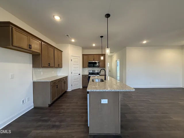 a large kitchen with stainless steel appliances granite countertop a sink a stove and a wooden floor