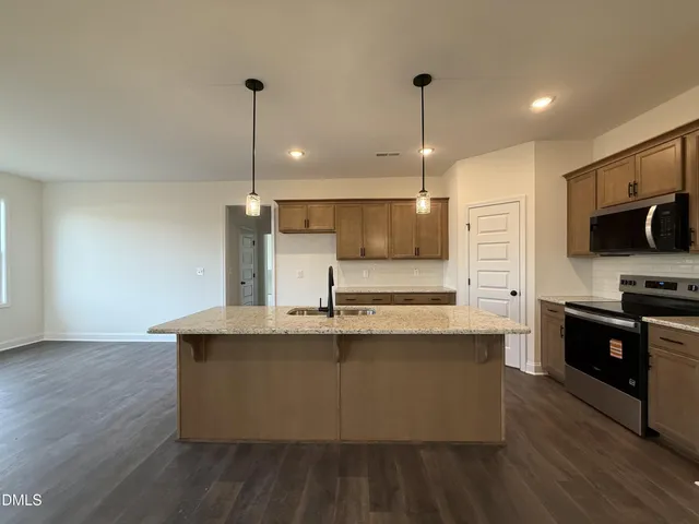 a kitchen with stainless steel appliances granite countertop a sink a stove and a wooden floors