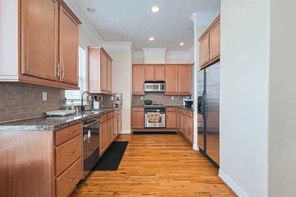 a large kitchen with stainless steel appliances granite countertop a stove top oven a sink and dishwasher