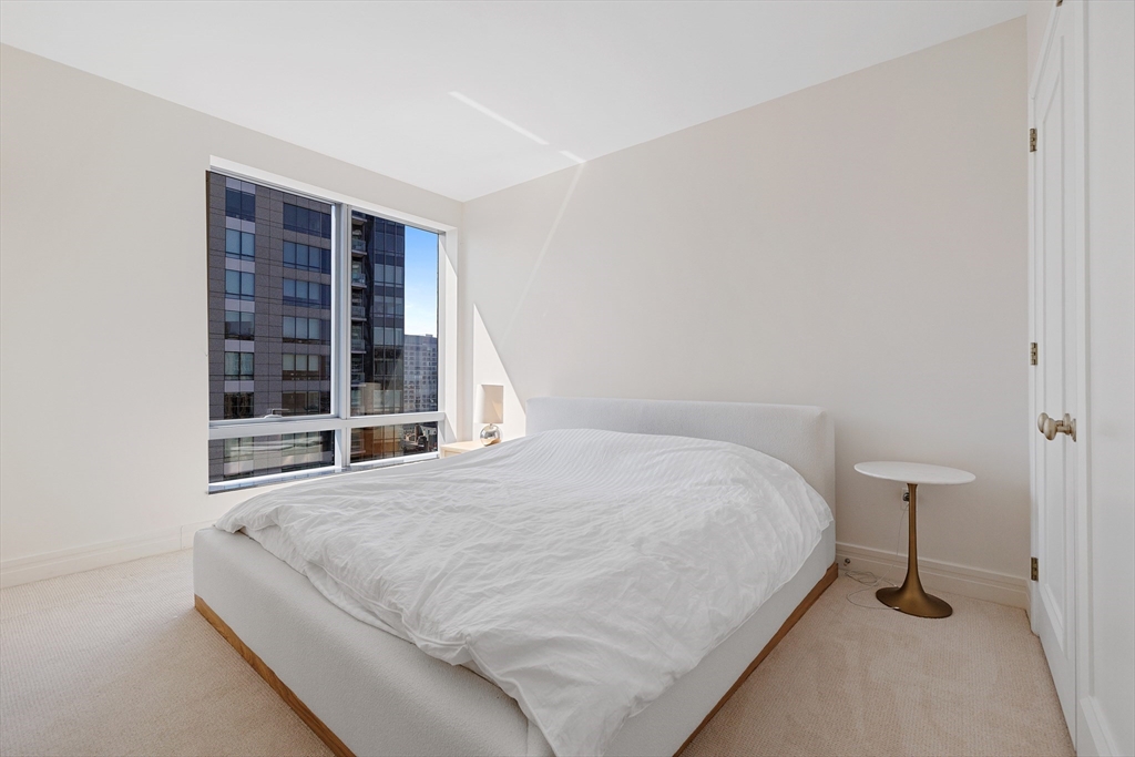 1 Avery Street, Unit 23C Boston, MA 02111 - Photo 11 of 22 a large bed sitting in a bedroom next to a window and a lamp
