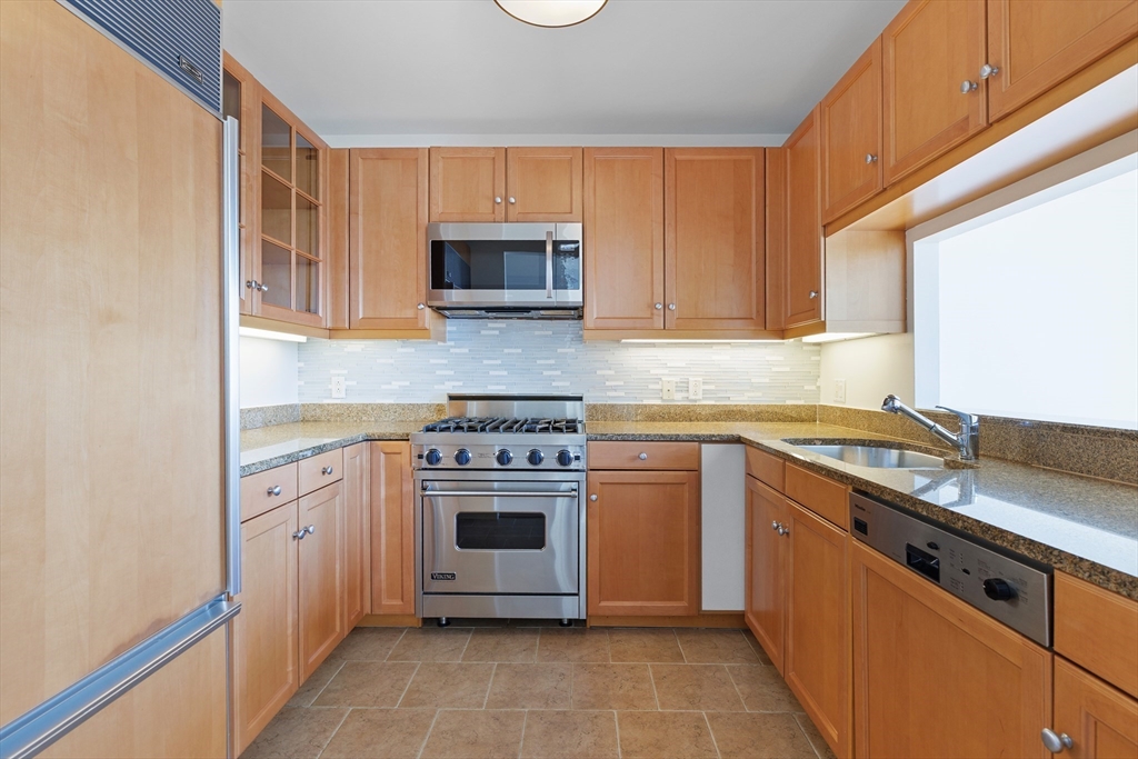 1 Avery Street, Unit 23C Boston, MA 02111 - Photo 9 of 22 a kitchen with stainless steel appliances granite countertop a stove a sink and a microwave