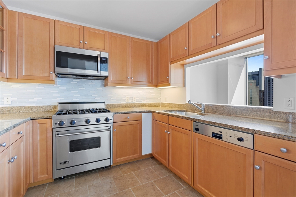 1 Avery Street, Unit 23C Boston, MA 02111 - Photo 10 of 22 a kitchen with stainless steel appliances granite countertop a stove and a microwave