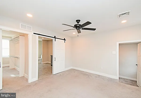 a view of a livingroom with a ceiling fan & windows