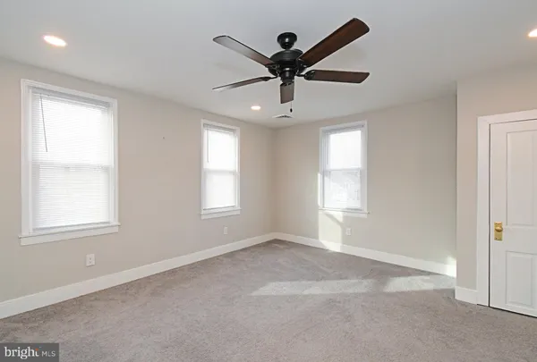 a view of a white house next to a yard with big trees