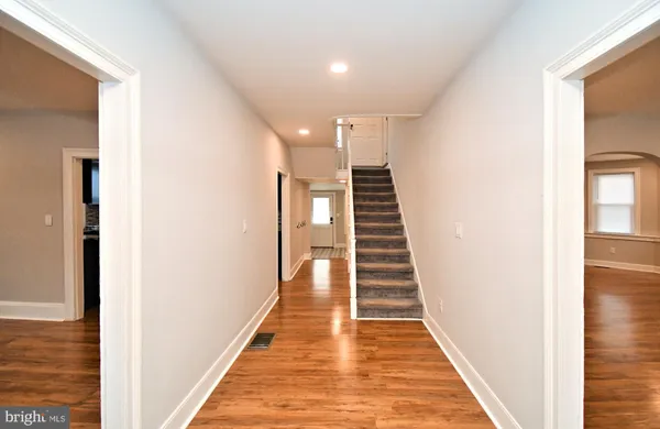 an empty room with wooden floor a ceiling fan and windows