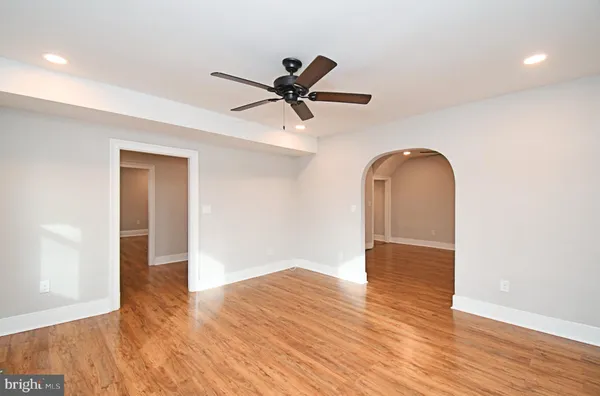 a view of empty room with wooden floor and ceiling fan