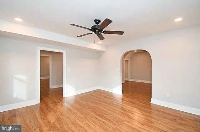 a view of empty room with wooden floor and ceiling fan