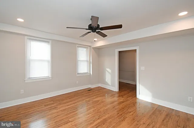 a view of empty room with wooden floor and fan