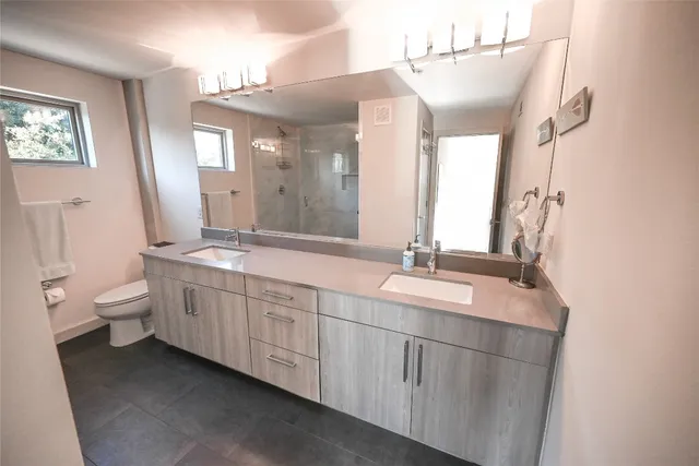a bathroom with double vanity sink a mirror and a toilet