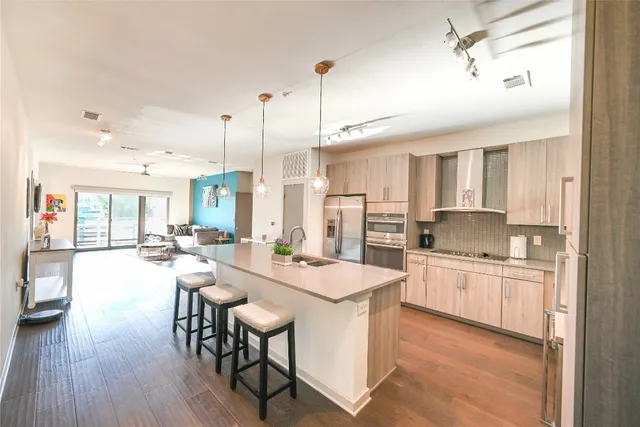 a kitchen with stainless steel appliances kitchen island granite countertop a stove a sink a dining table and chairs
