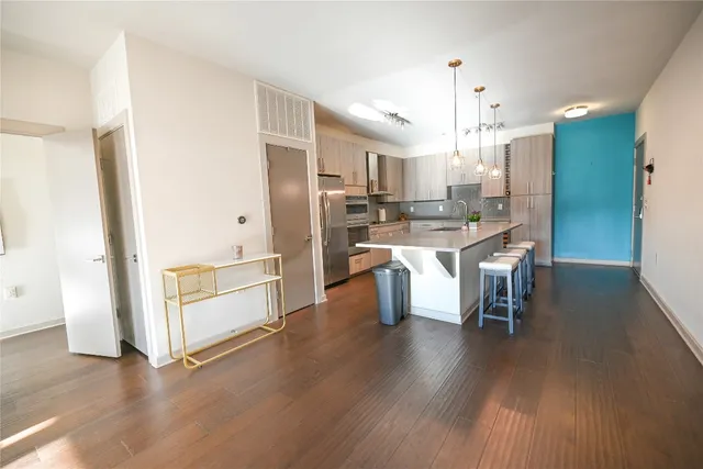 a kitchen with stainless steel appliances a dining table chairs and wooden floor