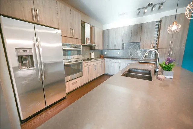 a kitchen with stainless steel appliances granite countertop a refrigerator a sink and a stove
