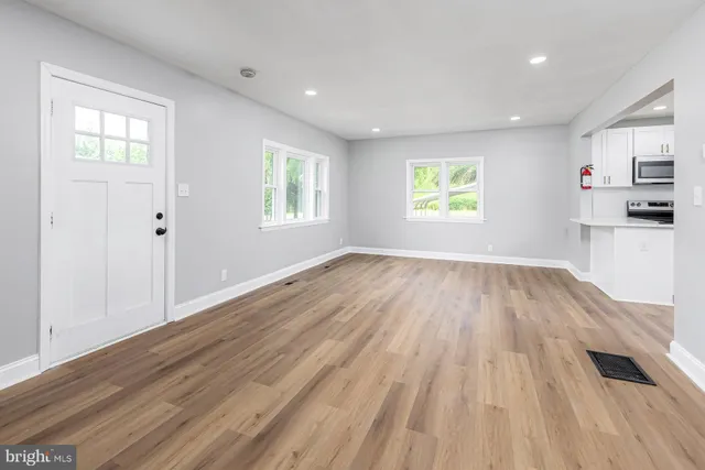 an empty room with wooden floor and windows