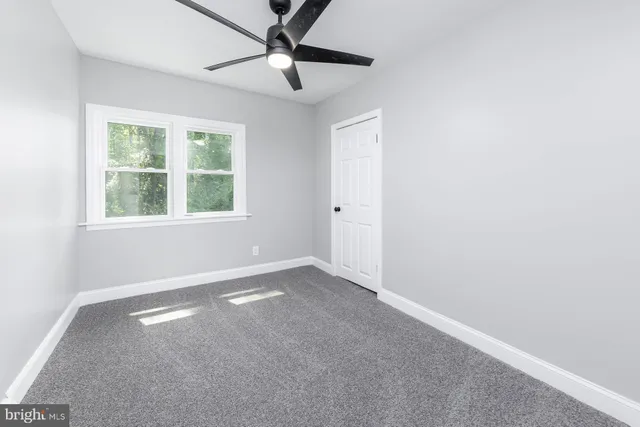 an empty room with a window and a fan