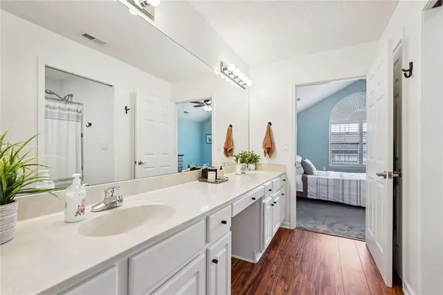 a bathroom with a granite countertop double vanity sink a mirror a vanity and a bathtub