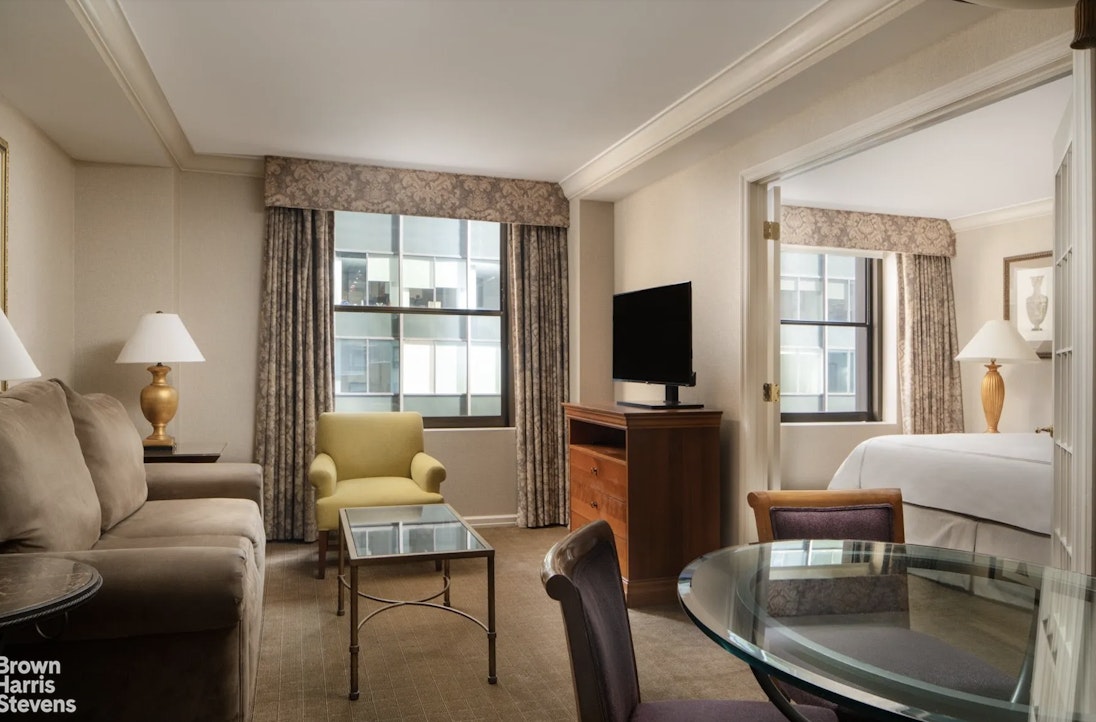 200 West 56th Street, Unit 1705 Manhattan, NY 10019 - Photo 3 of 12 a living room with furniture a flat screen tv and a large window