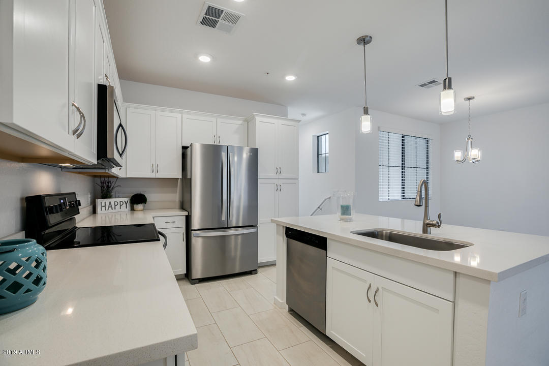 3900 East Baseline Road, Unit 114 Phoenix, AZ 85042 - Photo 9 of 31 a kitchen with stainless steel appliances kitchen island a sink a refrigerator and chairs