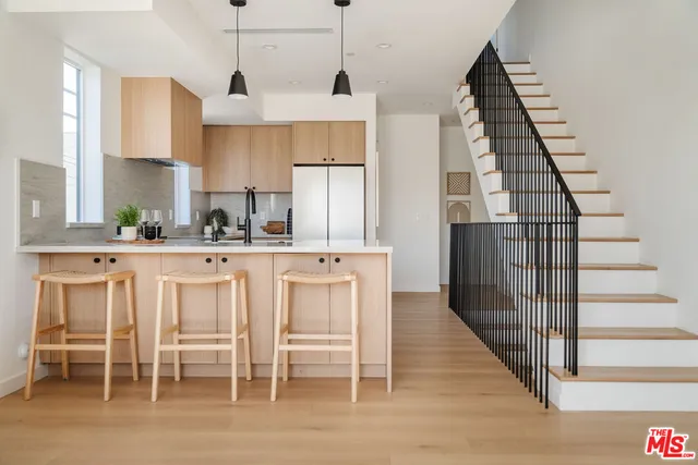 a kitchen with stainless steel appliances kitchen island granite countertop a table chairs in it and wooden floors