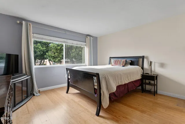 a bedroom with a bed closet and a flat tv screen next to a window