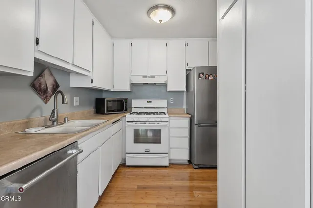 a kitchen with a sink cabinets stainless steel appliances and a window