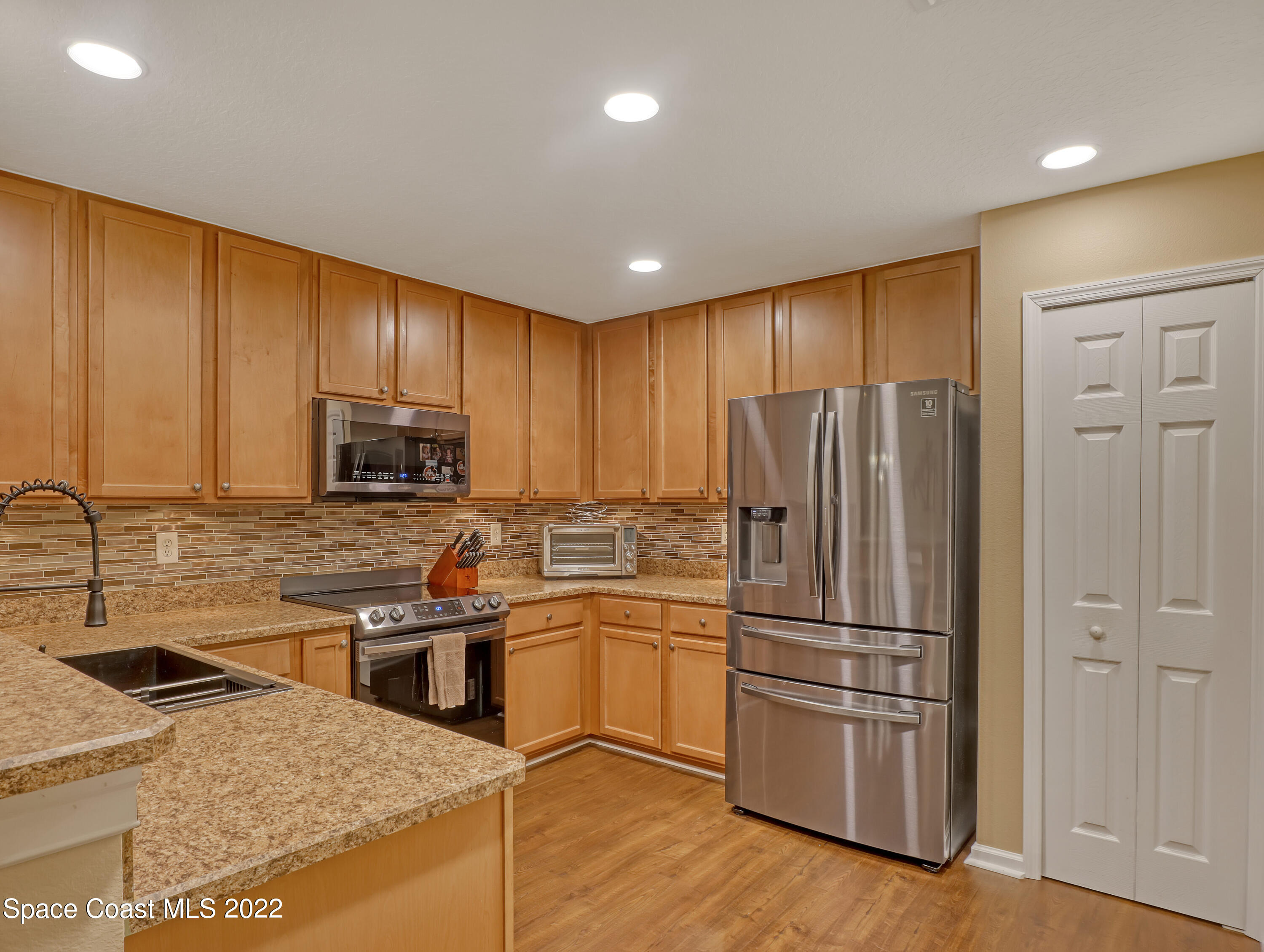 4077 Meander Place Rockledge, FL 32955 - Photo 4 of 24 a kitchen with kitchen island granite countertop stainless steel appliances and wooden cabinets